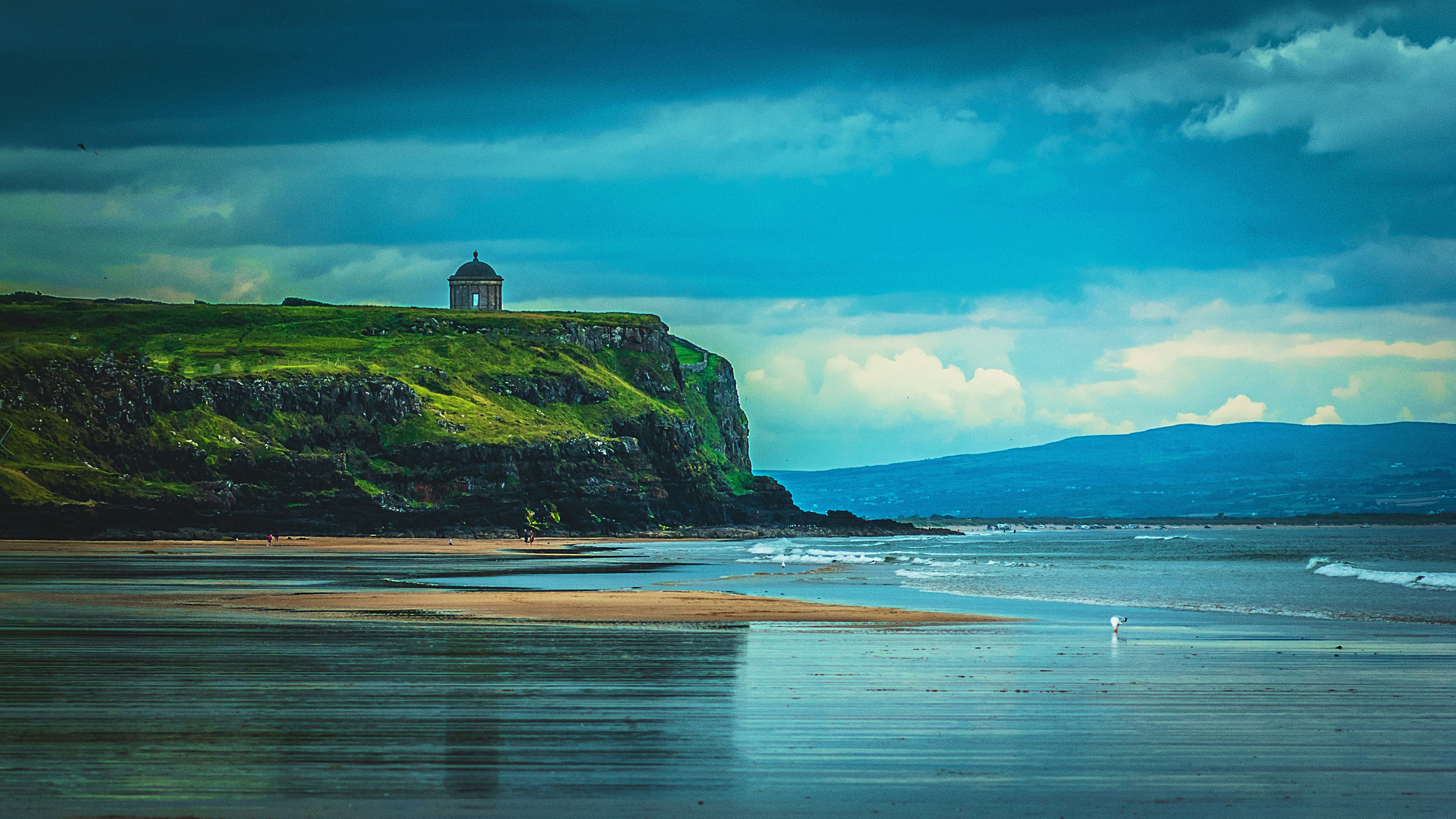 white and black chapel near cliff in front of body of water